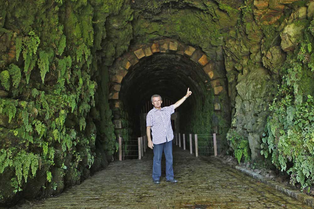 A entrada do antigo túnel com um arco de pedras. Ao longo dos seus 429 metros de extensão, o túnel ora apresenta revestimento com blocos de pedra ora está na rocha bruta da montanha. (Foto: Jonathan Campos/GP)